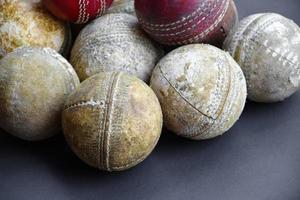 Old training cricket sport equipments on dark floor, leather ball, wickets, helmet and wooden bat, soft and selective focus, traditional cricket sport lovers around the world concept. photo