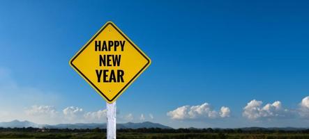 señal de tráfico de etiqueta amarilla en el poste blanco que tiene textos 'feliz año nuevo', concepto para informar feliz año nuevo a los conductores en el camino. foto