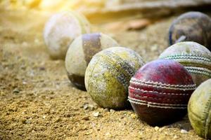 viejas pelotas de cricket de cuero para entrenar y practicar en el suelo de arena al lado de la cancha, enfoque suave y selectivo en la pelota de cricket roja. foto