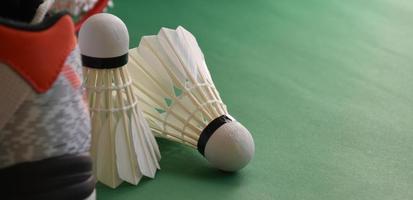 Badminton sport equipments on green floor of badminton court shuttlecocks, rackets, shoes, selective focus on shuttlecocks, badminton sport playing lover around the world concept. photo