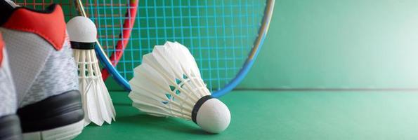 Badminton sport equipments on green floor of badminton court shuttlecocks, rackets, shoes, selective focus on shuttlecocks, badminton sport playing lover around the world concept. photo