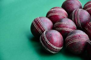 Old training cricket sport equipments on dark floor, leather ball, wickets, helmet and wooden bat, soft and selective focus, traditional cricket sport lovers around the world concept. photo