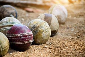 viejas pelotas de cricket de cuero para entrenar y practicar en el suelo de arena al lado de la cancha, enfoque suave y selectivo en la pelota de cricket roja. foto