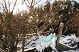 blue used mask on wood, face mask pollution of nature, Discarded coronavirus single-use face masks, Garbage in the streets threatens the environment, a mask on a tree in a park photo