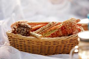 cesta de mimbre con pan. pan, bollos y grissini dentro de la cesta. productos de panadería frescos en un picnic. enfoque selectivo foto