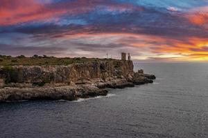 Idyllic view of seascape by cliff against dramatic sky during sunset photo