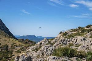 Airplane flying over rocky mountain at island against blue sky photo