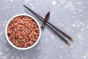 arroz rojo en un recipiente aislado sobre fondo gris. comida asiática cocinada. foto