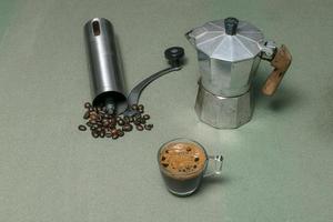 El café espresso casero de la mañana tiene una cafetera moka en una mesa de madera verde. foto