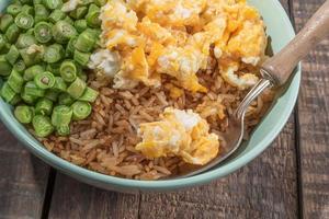 Egg fried rice and bean in green bowl on wood table. photo