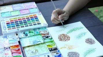 Lady is drawing pinecone using watercolor - people with Christmas celebration art hand draw watercolor concept video