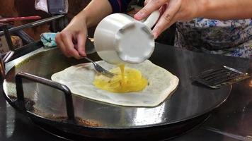 Lady is cooking sweet roti with egg and banana - asian dessert food preparation concept video