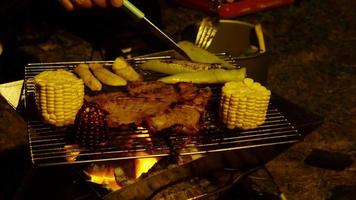 Closeup of coal grill barbecue with fresh delicious meat and vegetable during evening camping activity - camping cooking concept video
