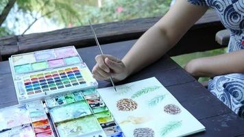 dame tekent dennenappel met behulp van aquarel - mensen met kerstviering kunst hand tekenen aquarel concept video