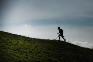 Caminata nórdica cuesta arriba en una pradera montañosa en silueta foto