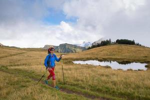 Lonely girl practicing Nordic walking with hiking sticks in the mountains photo