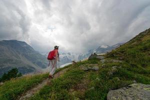 Retired woman practices a hike in the high mountains photo