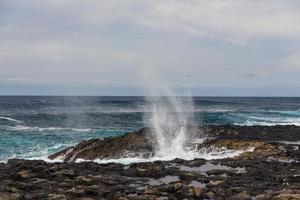 Turbulent ocean waves with white foam beat coastal stones photo