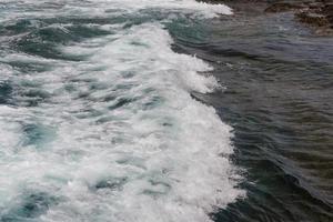 Las olas turbulentas del océano con espuma blanca golpean las piedras costeras. foto