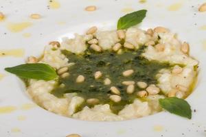 photo of delicious risotto dish with herbs and cedar nut on white background