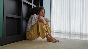 Latin woman sitting on floor feels unhappy by personal problems, break up or ruined marriage photo