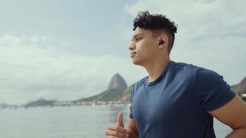 Young man running while listening to music on his headphones at the Rio de Janeiro beach. photo