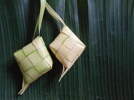 ketupat, arroz indonesio cocinado sobre fondo verde. ketupat es una cubierta de arroz natural hecha de hojas de coco jóvenes para cocinar arroz durante eid mubarak, eid ul fitr foto