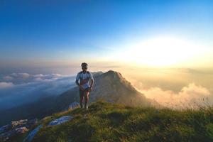 Mountain runner training at sunset with clouds below photo