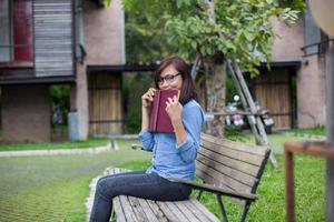 Hipster charming girl relaxing in the park while read book, Enjoy nature around. photo