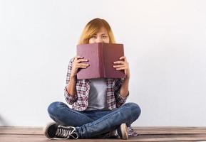 Young hipster woman holding books and pointing up on isolated white background. photo