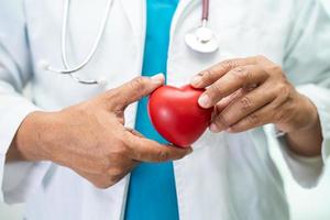 médico sosteniendo un corazón rojo en la sala del hospital, concepto médico fuerte y saludable. foto