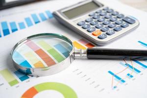 Magnifying glass and calculator on charts graphs paper. Financial development, Banking Account, Statistics, Investment Analytic research data economy, Stock exchange trading, Business office concept. photo