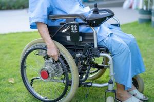 Paciente asiático mayor o anciano en silla de ruedas eléctrica con control remoto en la sala del hospital de enfermería, concepto médico fuerte y saludable foto