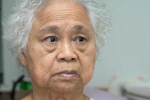 Asian elderly old woman face and eye with wrinkles, portrait closeup view. photo