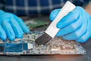 Technician use brush and air blower ball to clean dust in circuit board computer. Repair upgrade and maintenance technology. photo