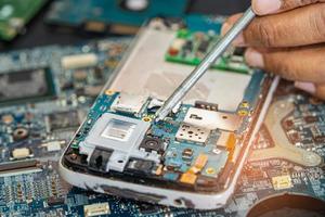 Technician repairing inside of mobile phone by soldering iron. Integrated Circuit. the concept of data, hardware, technology. photo