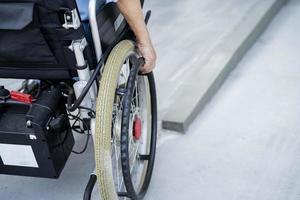 Paciente asiático mayor o anciano en silla de ruedas eléctrica con control remoto en la sala del hospital de enfermería, concepto médico fuerte y saludable foto