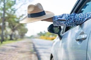 Happy enjoy and freedom in traveling trip with raised hand and holding beautiful hat outside of window car in summer vacation holiday photo