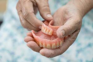 Asian senior or elderly old woman patient holding to use denture in nursing hospital ward, healthy strong medical concept photo
