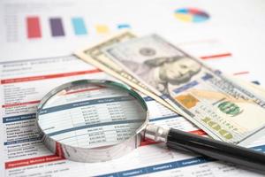 Magnifying glass and US dollar banknotes on spreadsheet and charts graphs paper. Financial development, Banking Account, Statistics, Investment Analytic research data economy. photo