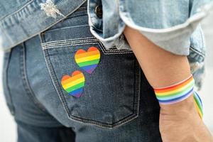 Asian lady wearing rainbow flag wristbands, symbol of LGBT pride month celebrate annual in June social of gay, lesbian, bisexual, transgender, human rights. photo