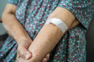 Asian senior or elderly old lady woman patient show cotton wool stop bleeding, after blood drawing testing for annually physical health check up to check cholesterol, blood pressure, and sugar level. photo