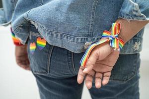 dama asiática con pulseras de la bandera del arco iris, símbolo del mes del orgullo lgbt celebran anualmente en junio las redes sociales de gays, lesbianas, bisexuales, transgénero, derechos humanos. foto