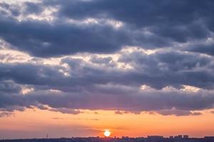 colorido paisaje nublado de puesta de sol con edificios de la ciudad en el horizonte. foto