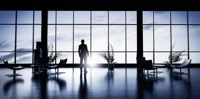 Business man standing in the office looking out of the window at sunset sky. photo