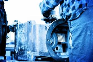 Workers repair, work on old gear element in workshop. Industry photo