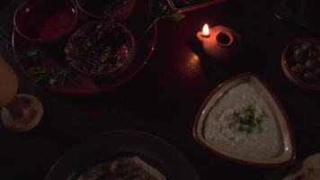 Spices, Sauces, Bread, Olives and Candles Fill a Table in a Dim Room video