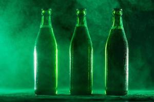 Three green beer bottles on a dusty background.