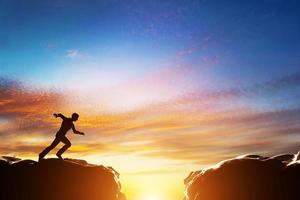 Man running fast to jump over precipice between two mountains. Challenge photo