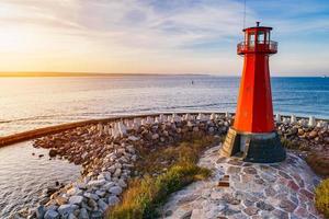 Red lighthouse on the rocky seashore. photo